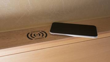 A smartphone on a wooden surface with a wireless charger symbol.