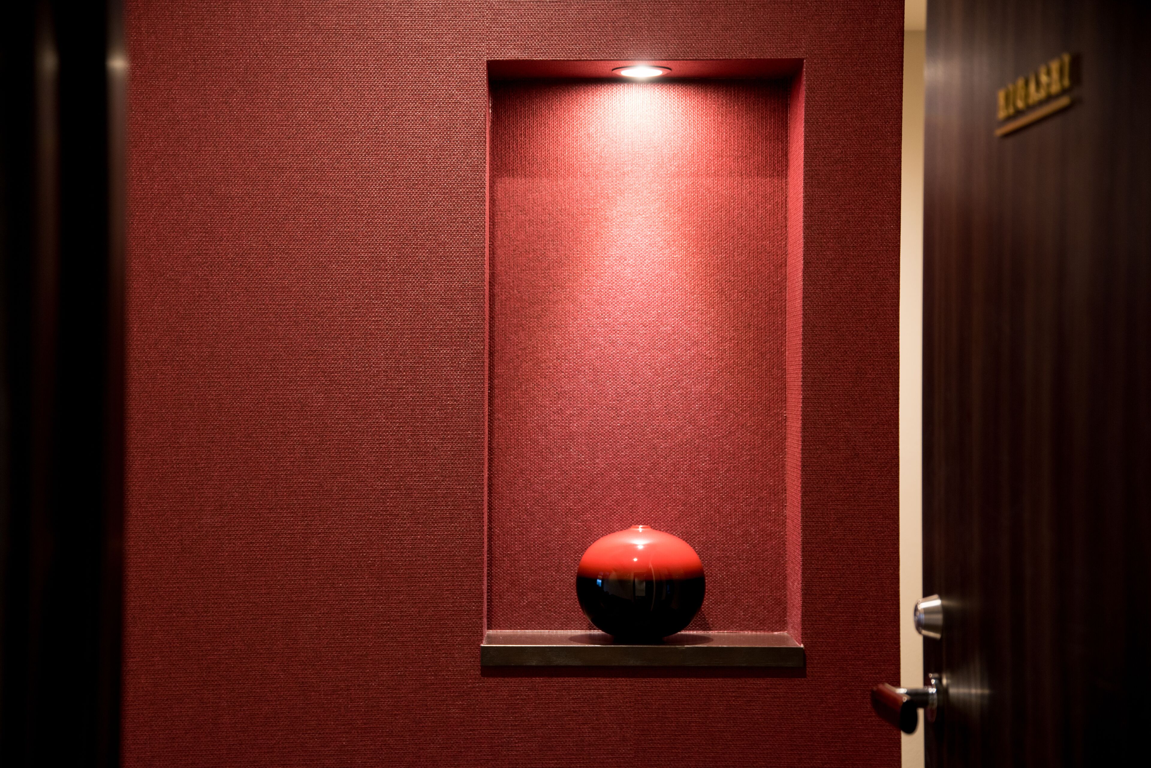 A red textured wall with a recessed shelf containing a spherical object.