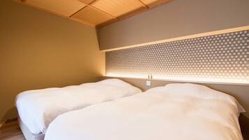 A bedroom with two beds, wooden ceiling, and a patterned wall headboard.