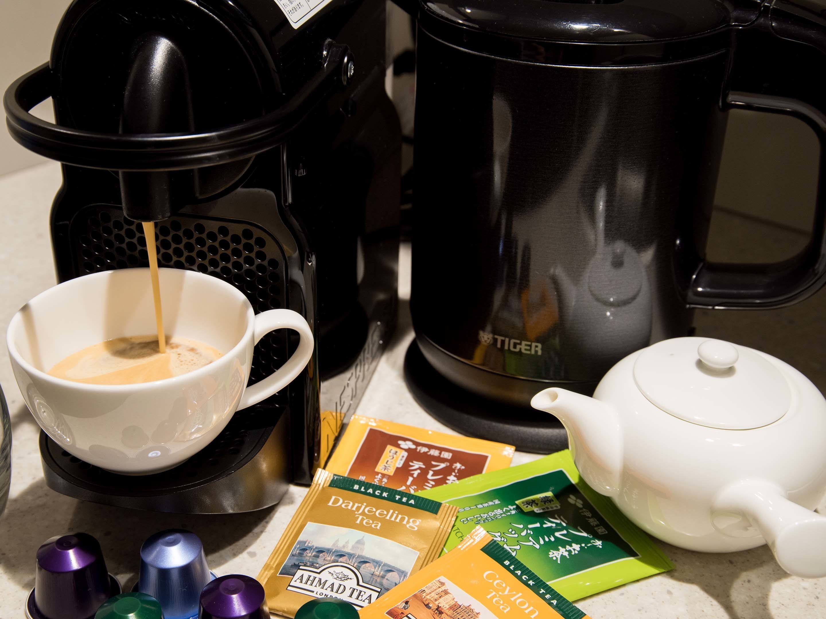 A coffee maker, a teapot, and tea packets on a countertop.