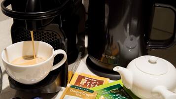 A coffee maker, a teapot, and tea packets on a countertop.
