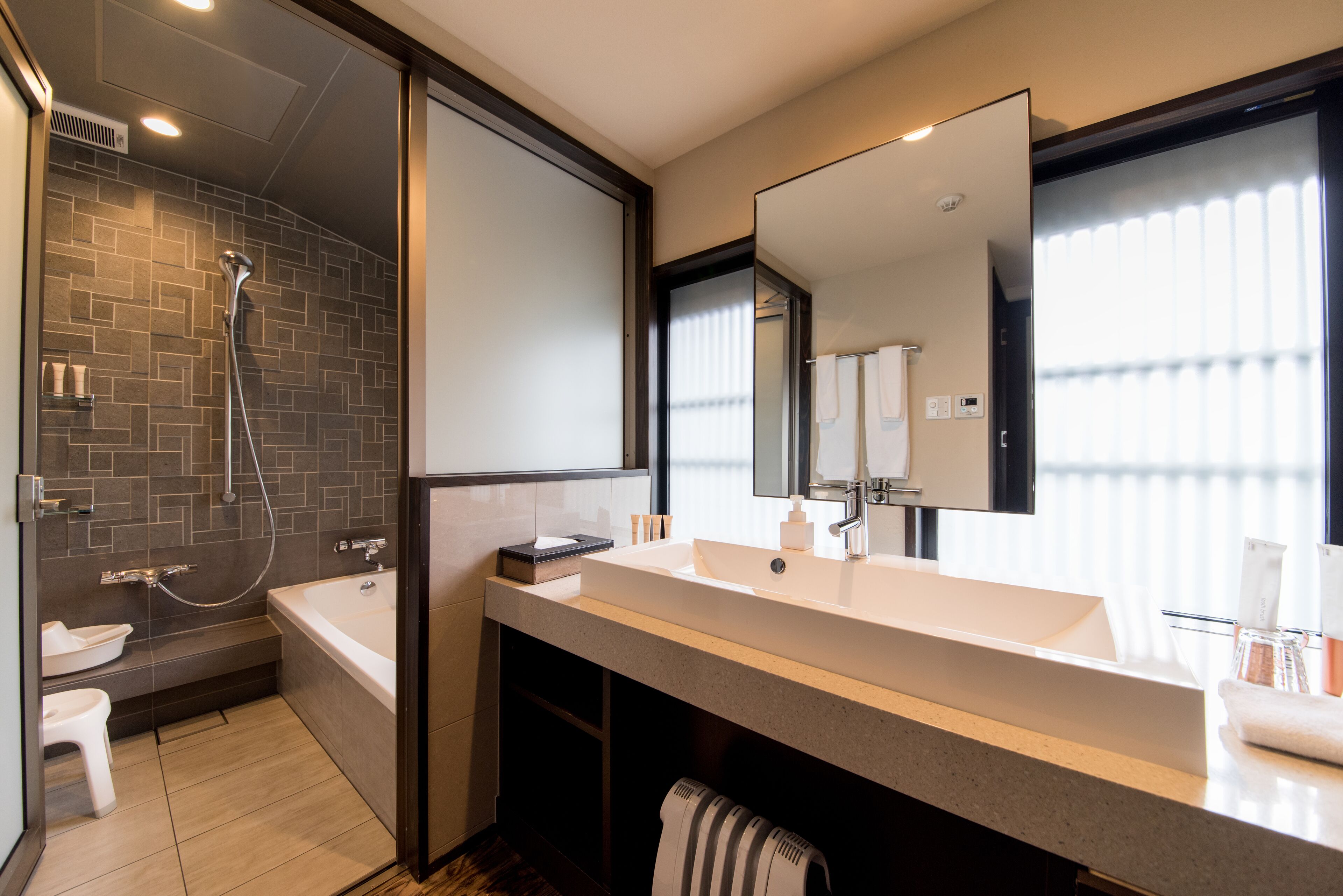 A modern bathroom with a shower, a bathtub, and a vanity with a large mirror.