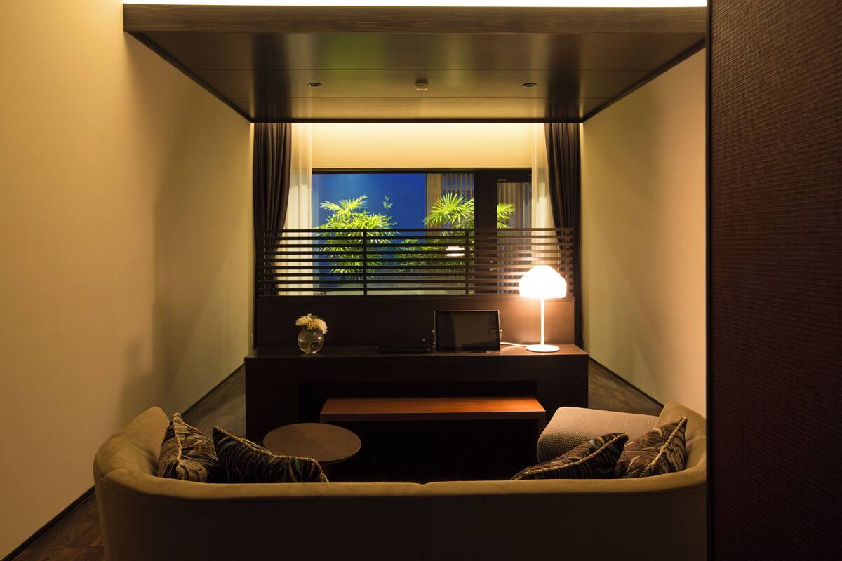 Un espace de vie compact comprenant un canapé, une petite table, une lampe et un téléviseur.