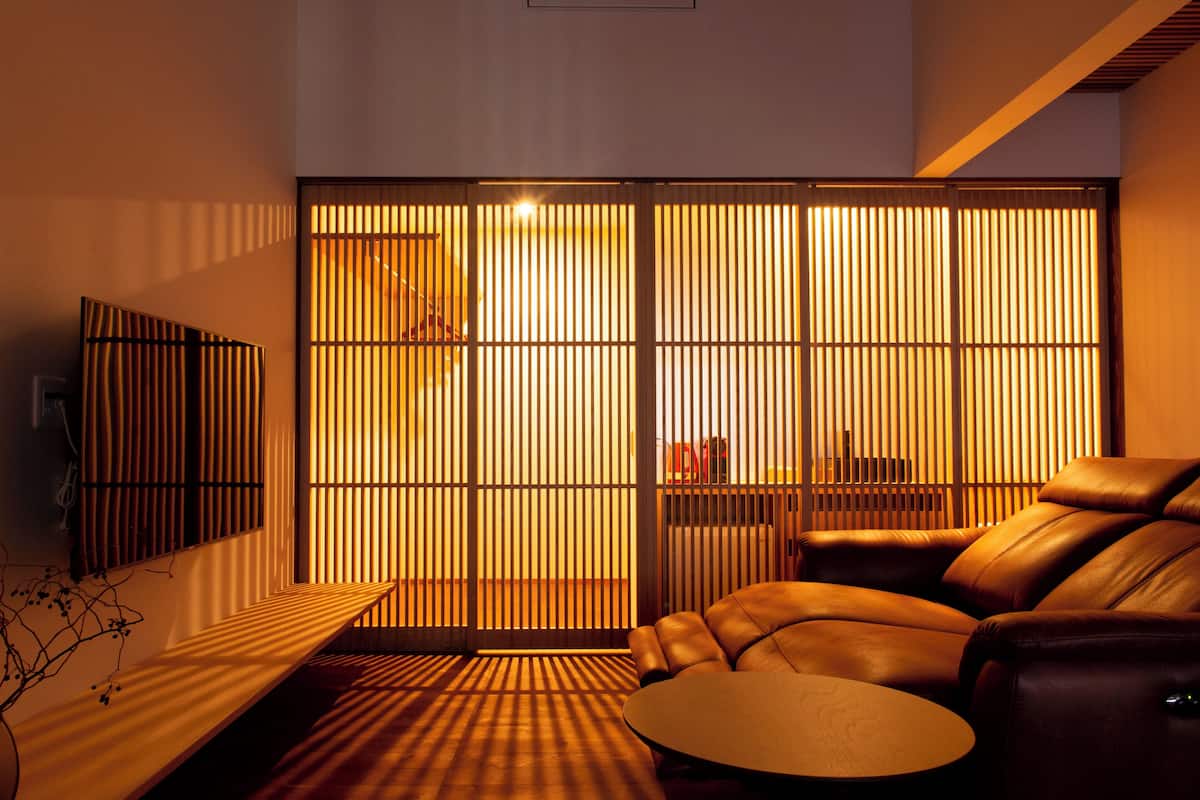 Un salon moderne avec un canapé en cuir, une table basse ronde et un paravent coulissant de style japonais.