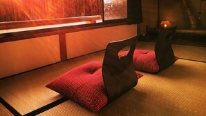 Een kamer met tatami matten, een lage tafel en twee kussens.