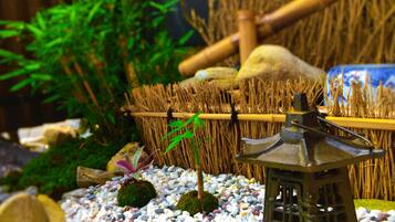 Un jardin miniature agrémenté d’une petite pagode, de galets, de mousse, de bambous et d’un panier en paille.