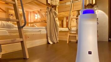 A bunk bed room with a standing heater and a suitcase.