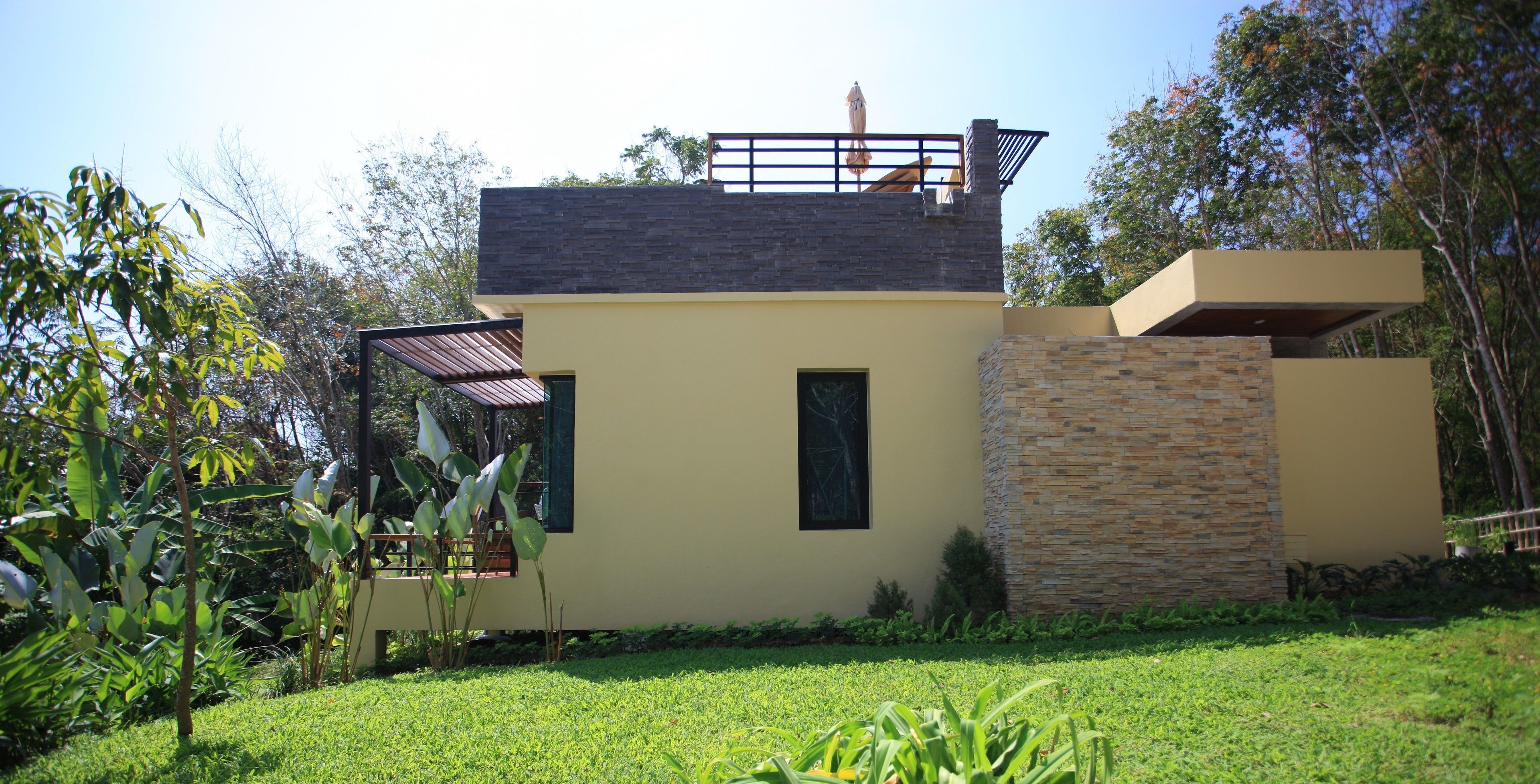 Una casa moderna con tetto piatto, un balcone e facciata in pietra.