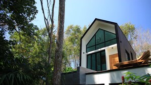 Una casa moderna con un amplio ventanal, rodeada de árboles.