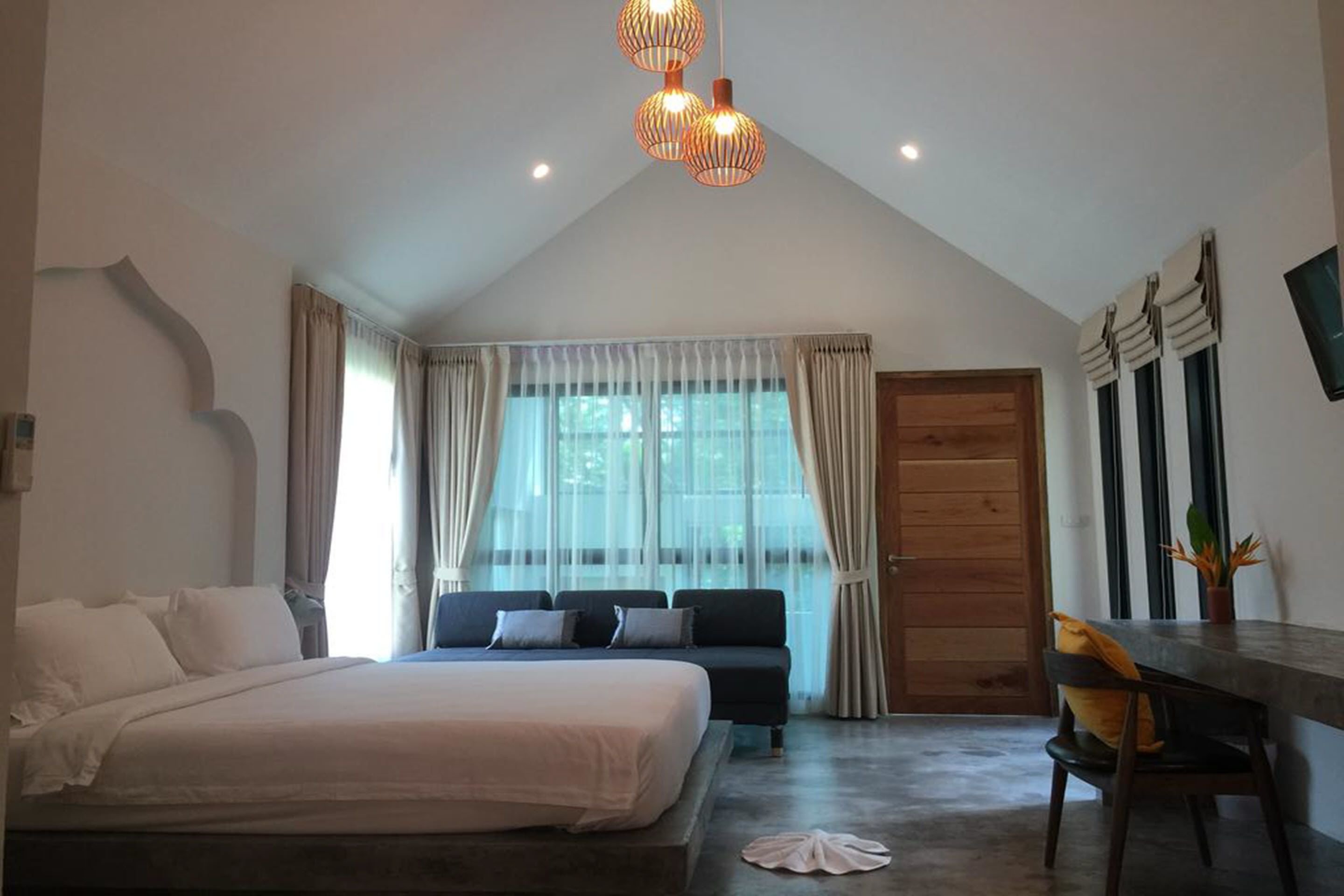 Un dormitorio con una cama grande, un sofá, un escritorio y una ventana con cortinas.