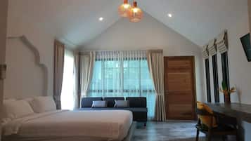 Un dormitorio con una cama grande, un sofá, un escritorio y una ventana con cortinas.