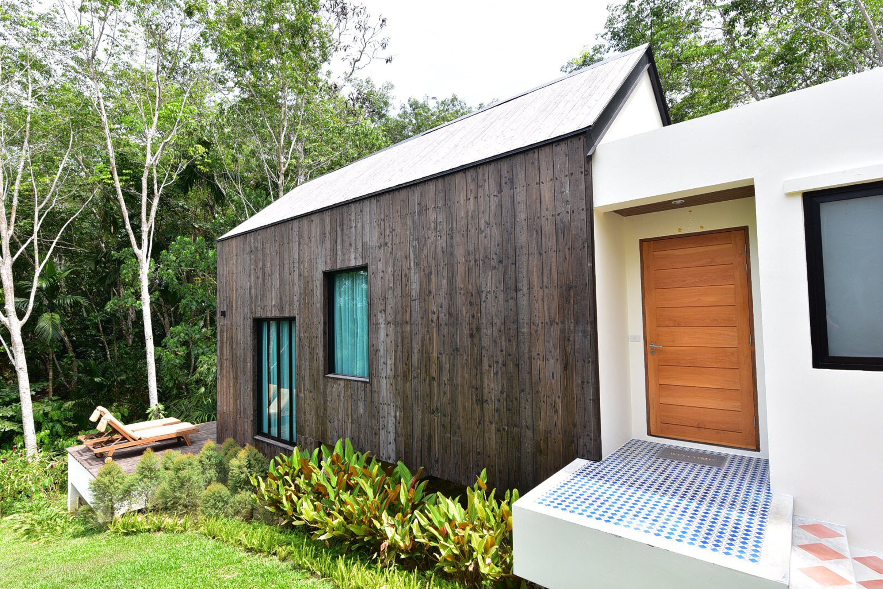 Una casa moderna con fachada de madera, una puerta principal y un pequeño porche.
