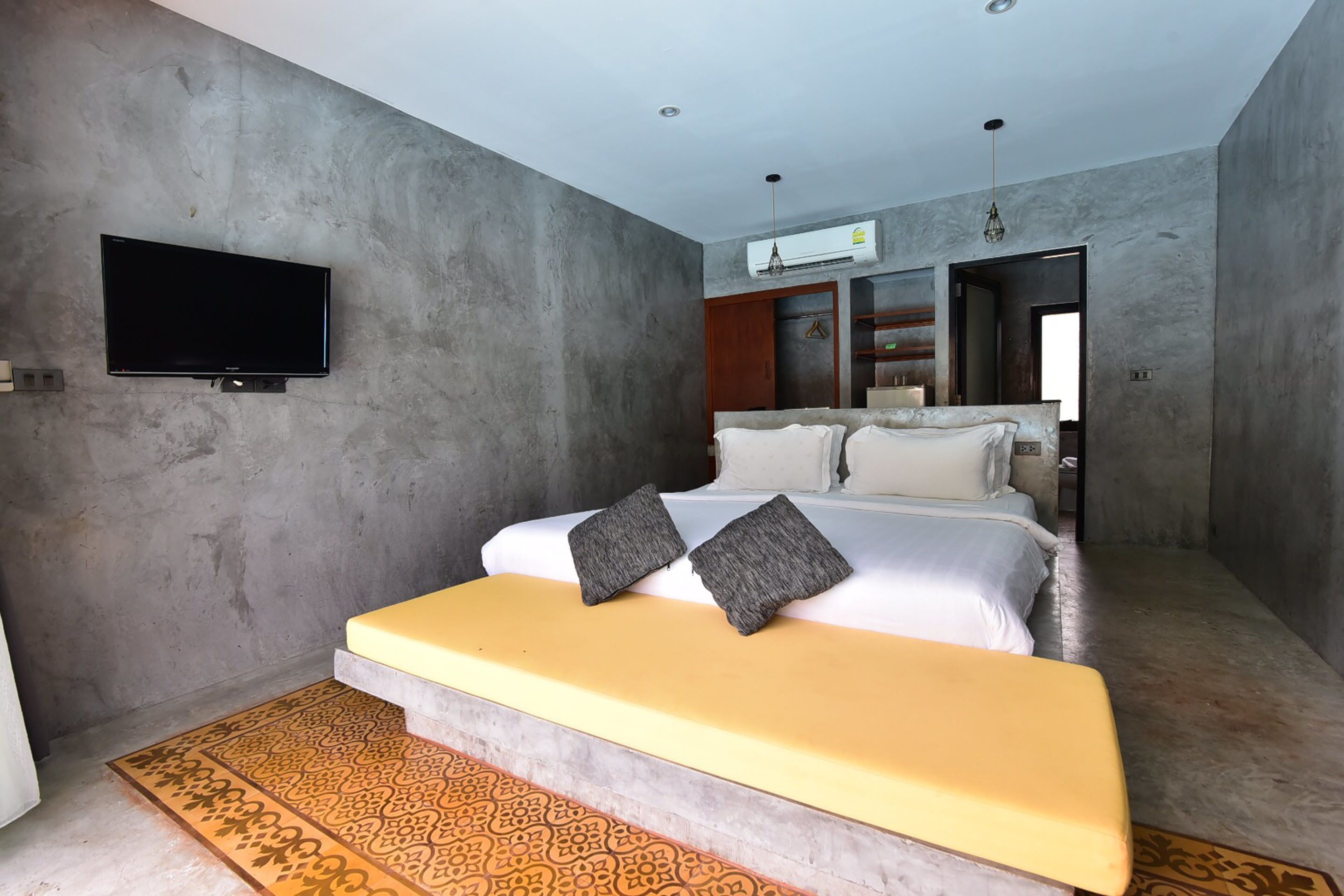 A modern bedroom with a large bed, a flat-screen TV mounted on the wall, and a built-in wardrobe.