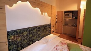 A bedroom with a bed, a wall-mounted light, and a built-in kitchen area.