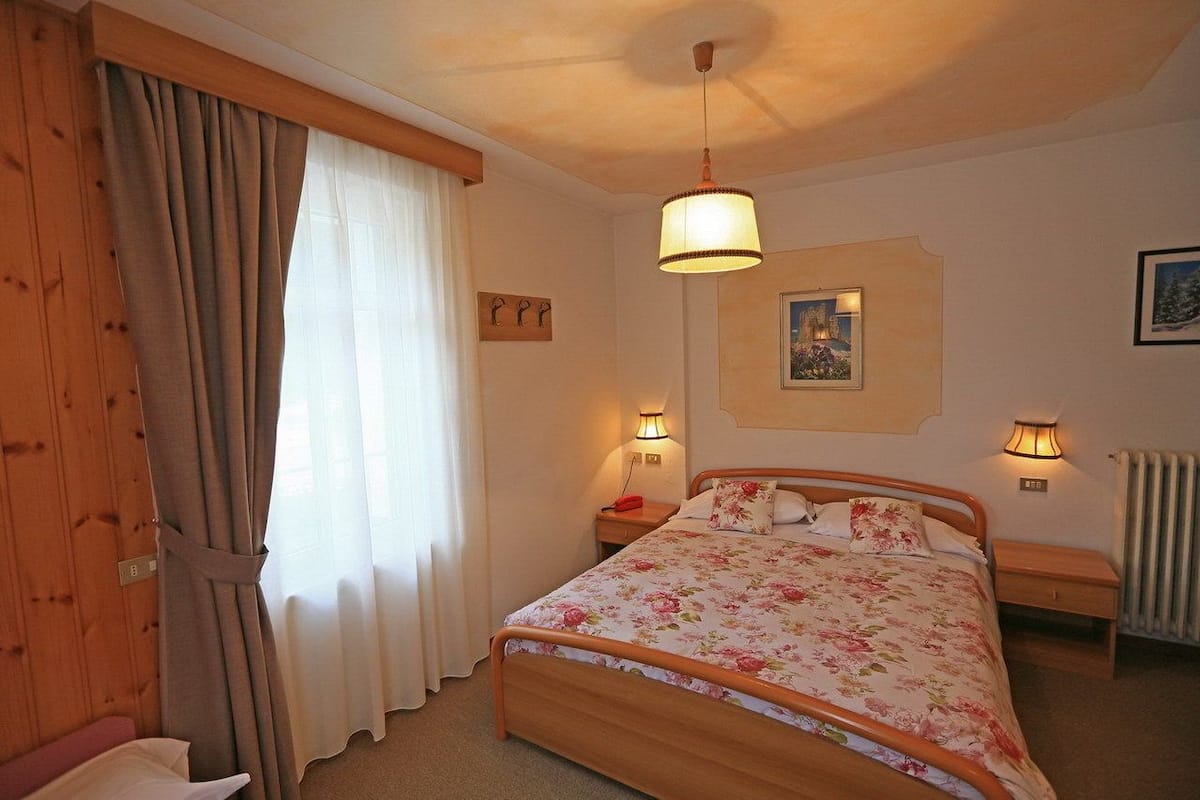 Ein Schlafzimmer mit einem Holzbett, zwei Nachttischen, einer Hängelampe und einer Heizung.