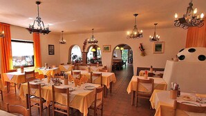 A restaurant with multiple tables and chairs, chandeliers, and framed pictures on the walls.
