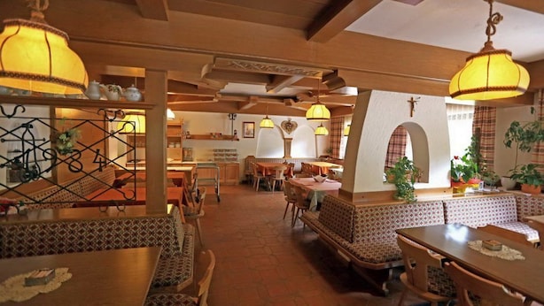 Ein Restaurant mit Holztischen, gemusterten Kissen und hängenden Lampen.