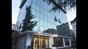 A modern hotel with a glass facade, a prominent entrance, and flags above the doors. - Grand Eyuboglu Hotel (Istanbul)