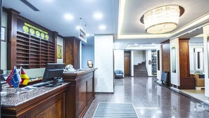 A hotel lobby with a reception desk, a chandelier, a staircase, and a wall displaying clocks. - Grand Eyuboglu Hotel (Istanbul)