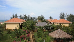 Un resort con varias construcciones, cada una con techo de tejas rojas, rodeado de exuberante follaje y palmeras.