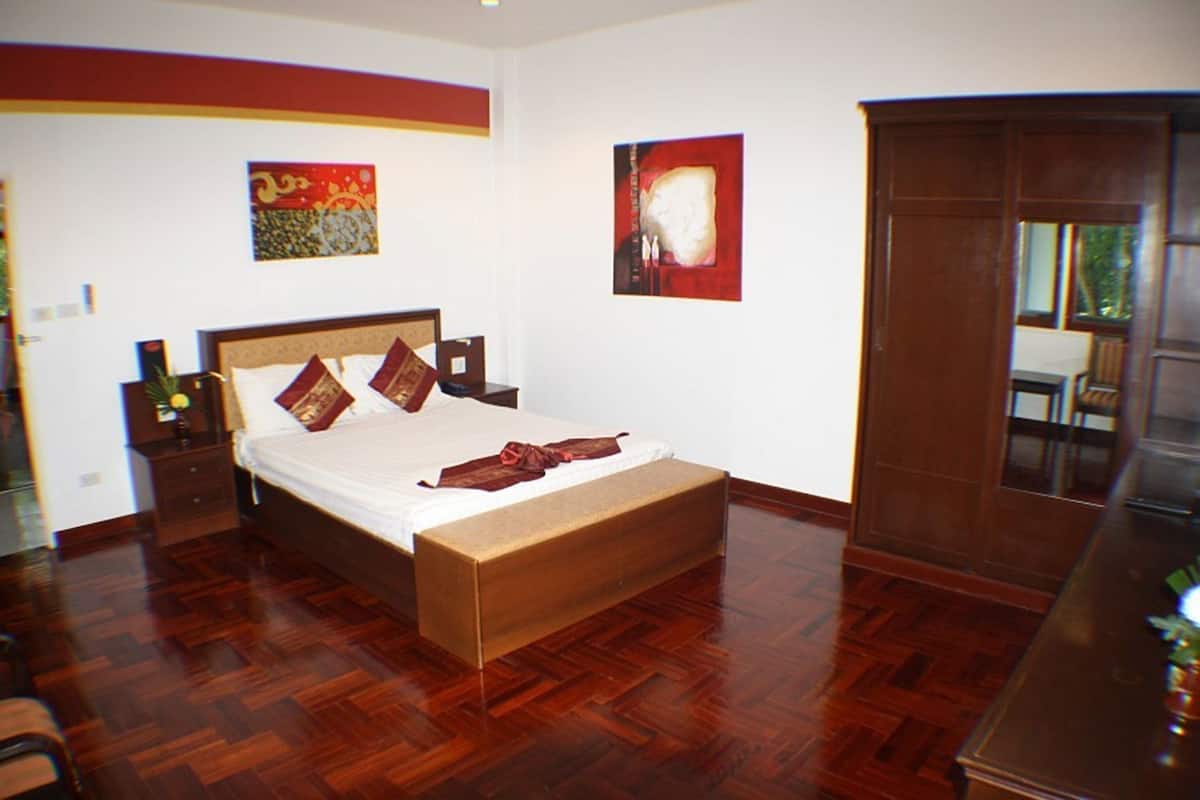 Ein Schlafzimmer mit einem hölzernen Bett, einem Nachttisch, einer Kommode und zwei Bildern an der Wand.