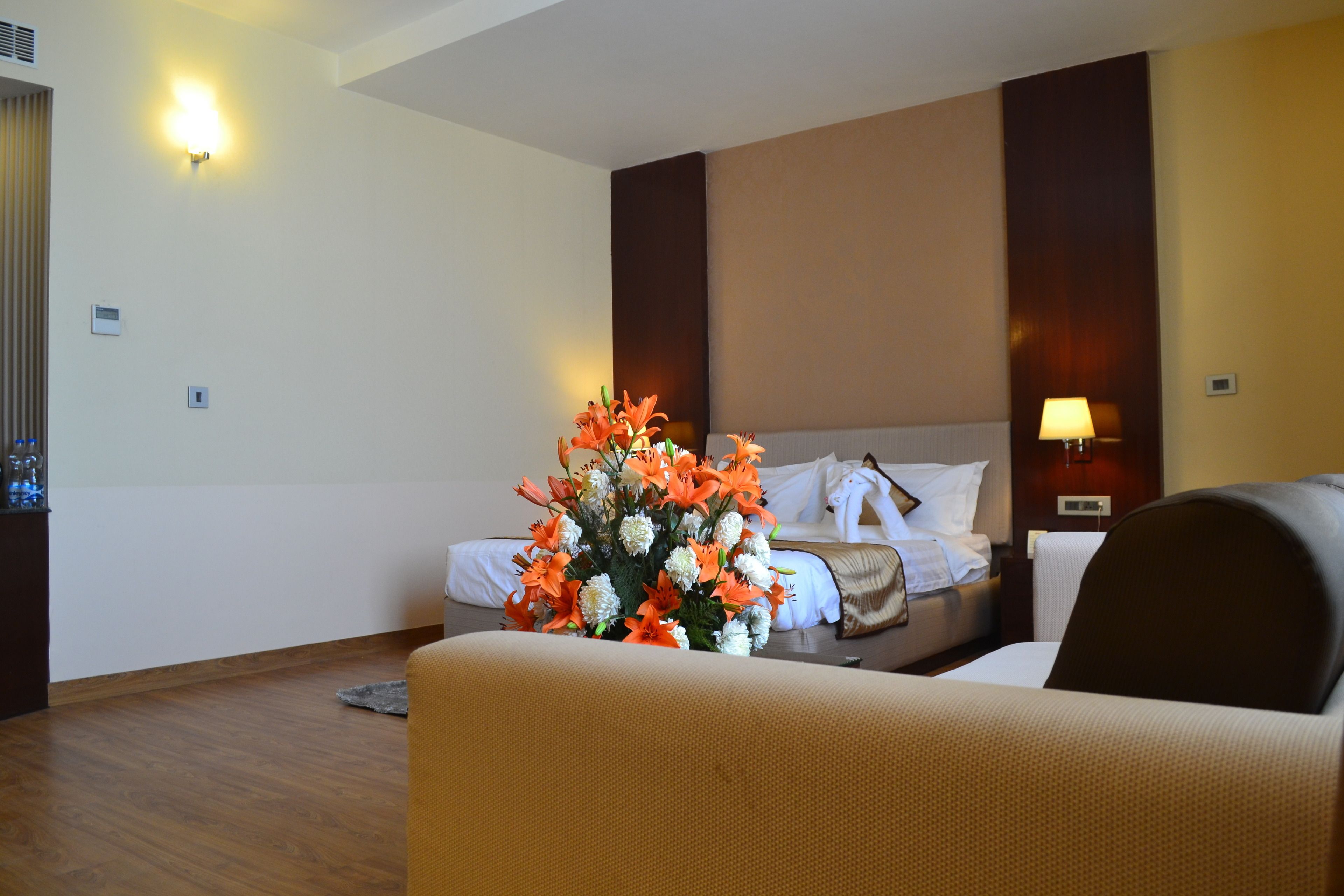 A hotel room with a bed, a nightstand, a lamp, and a floral arrangement.