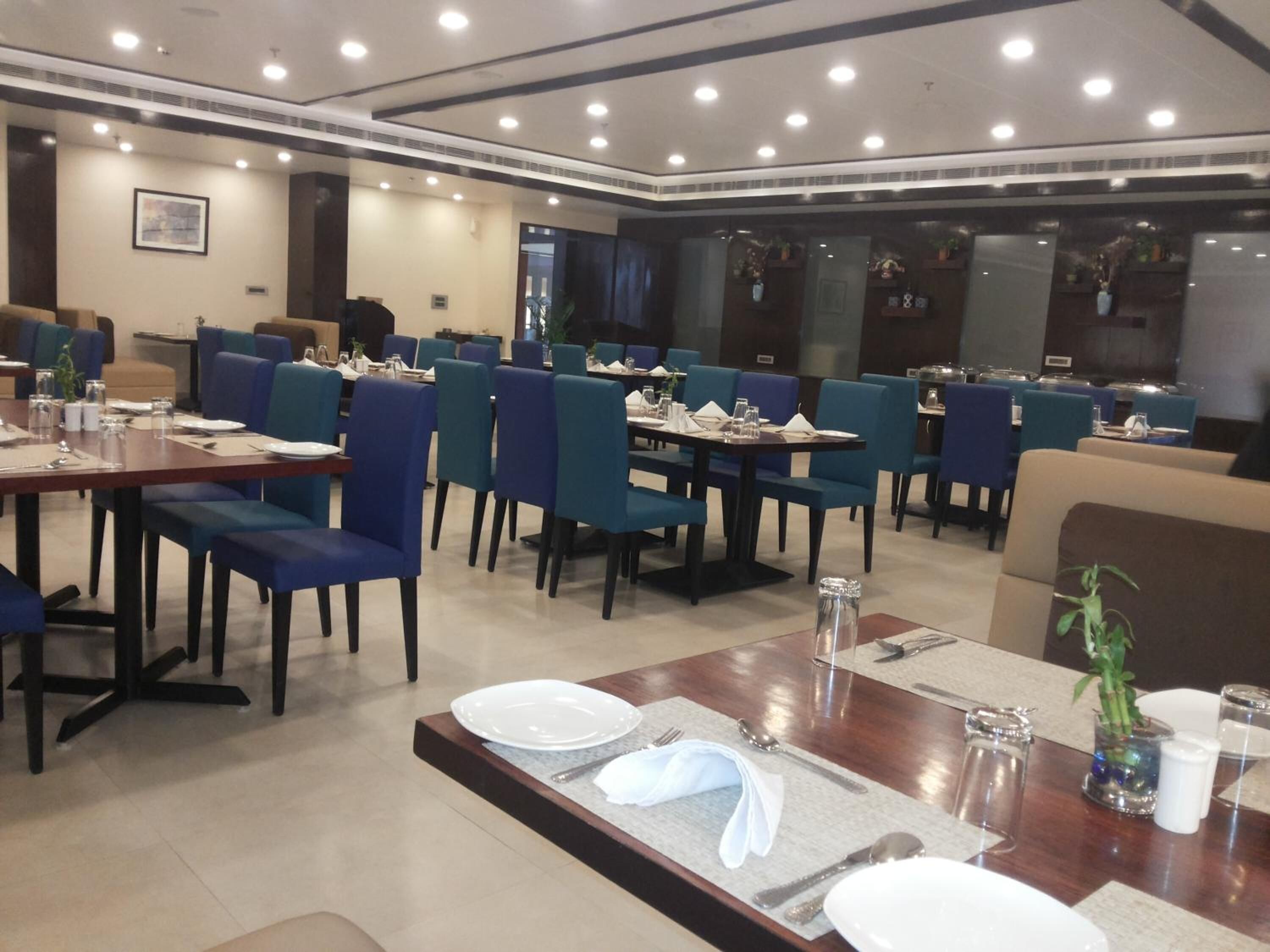 A spacious restaurant with multiple tables and chairs, well-lit with ceiling lights, and a modern interior design.