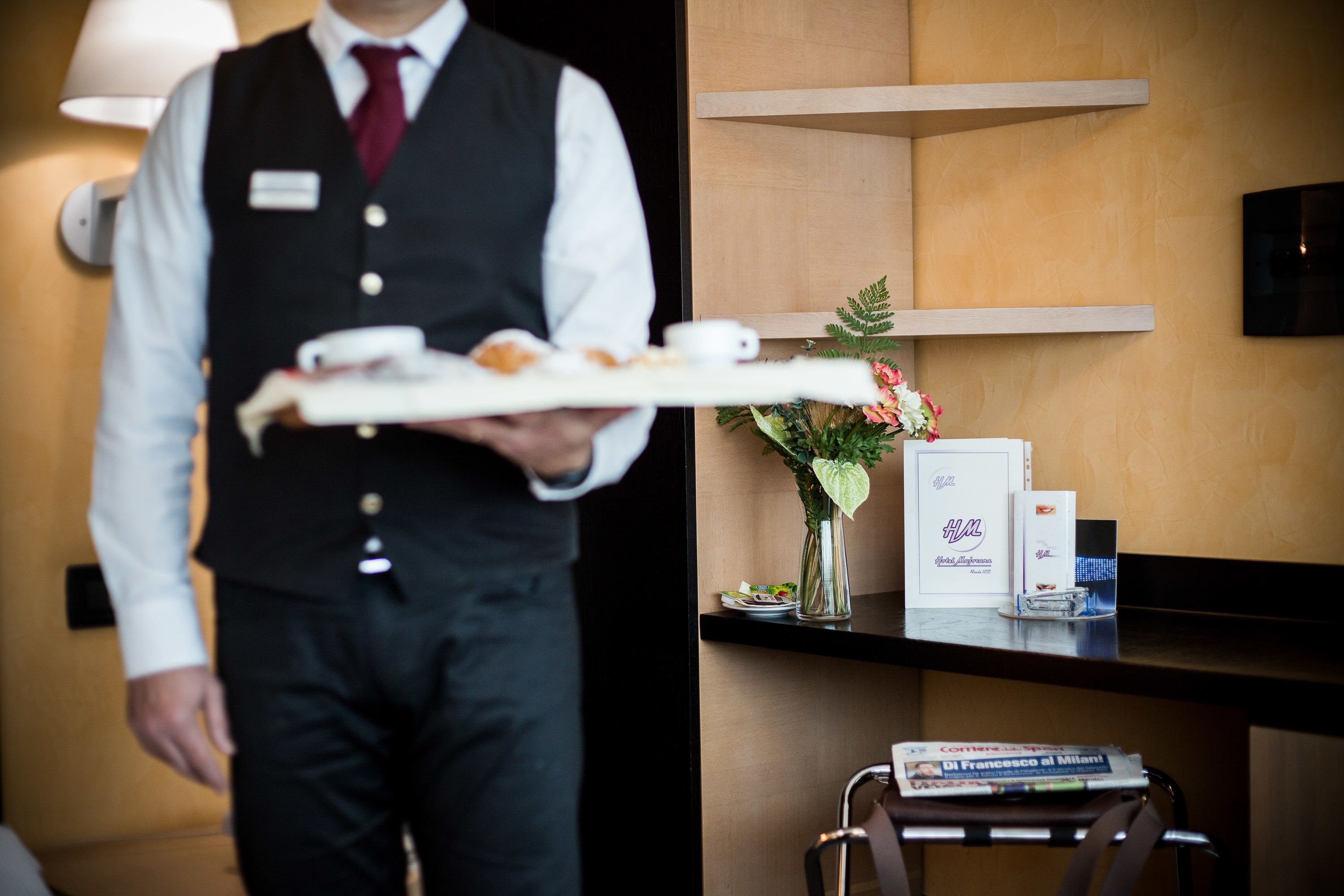A hotel reception area with a reception desk, a vase with flowers, and a magazine on the counter.