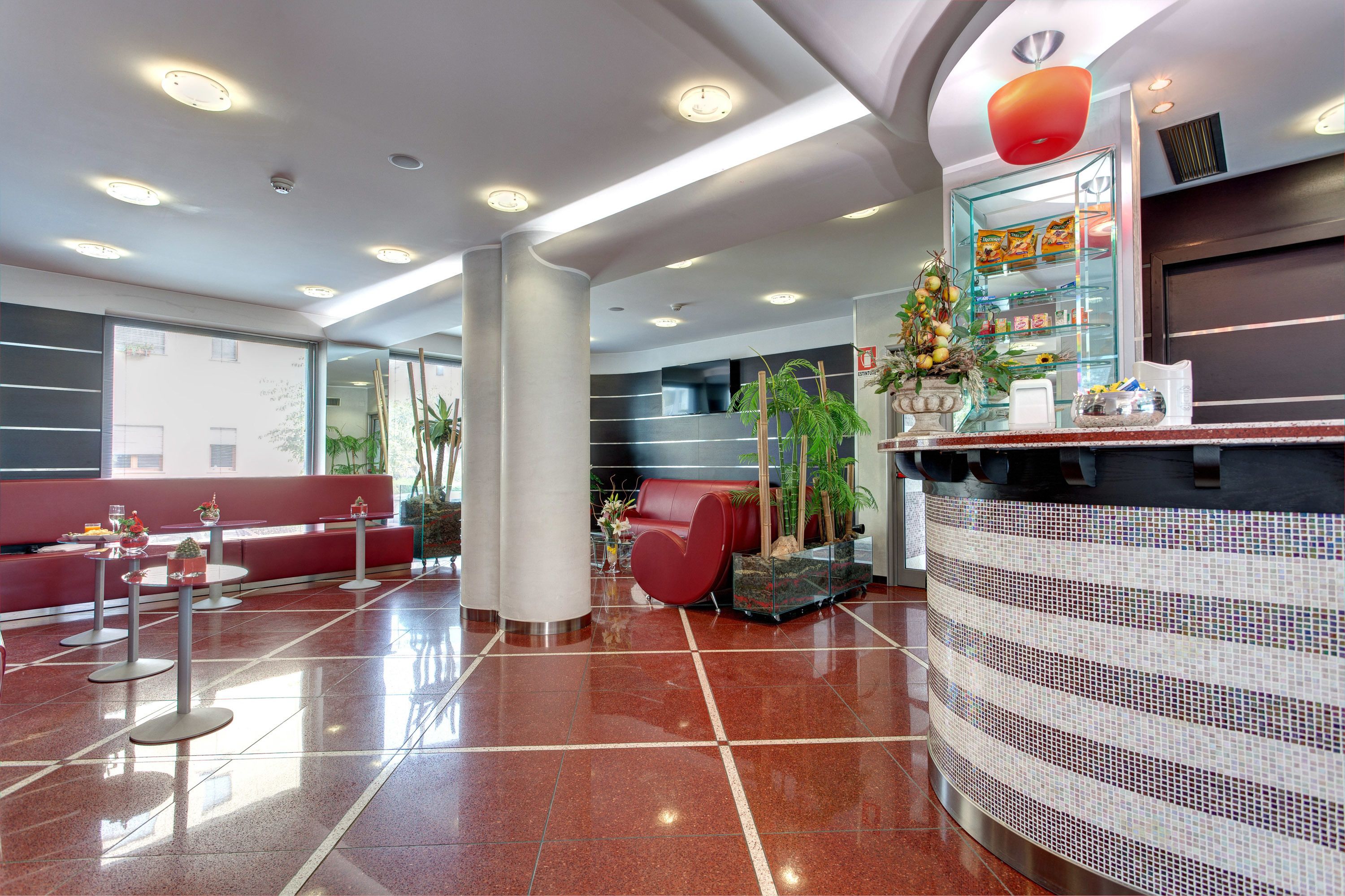 Un vestíbulo moderno con mostrador de recepción, zona de estar y grandes ventanales.