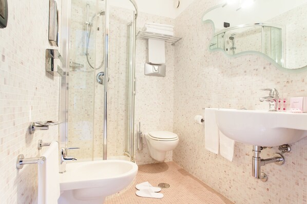 A bathroom with a glass shower enclosure, a toilet, and a sink with a mirror above it. - Hotel Majorana (Rende)