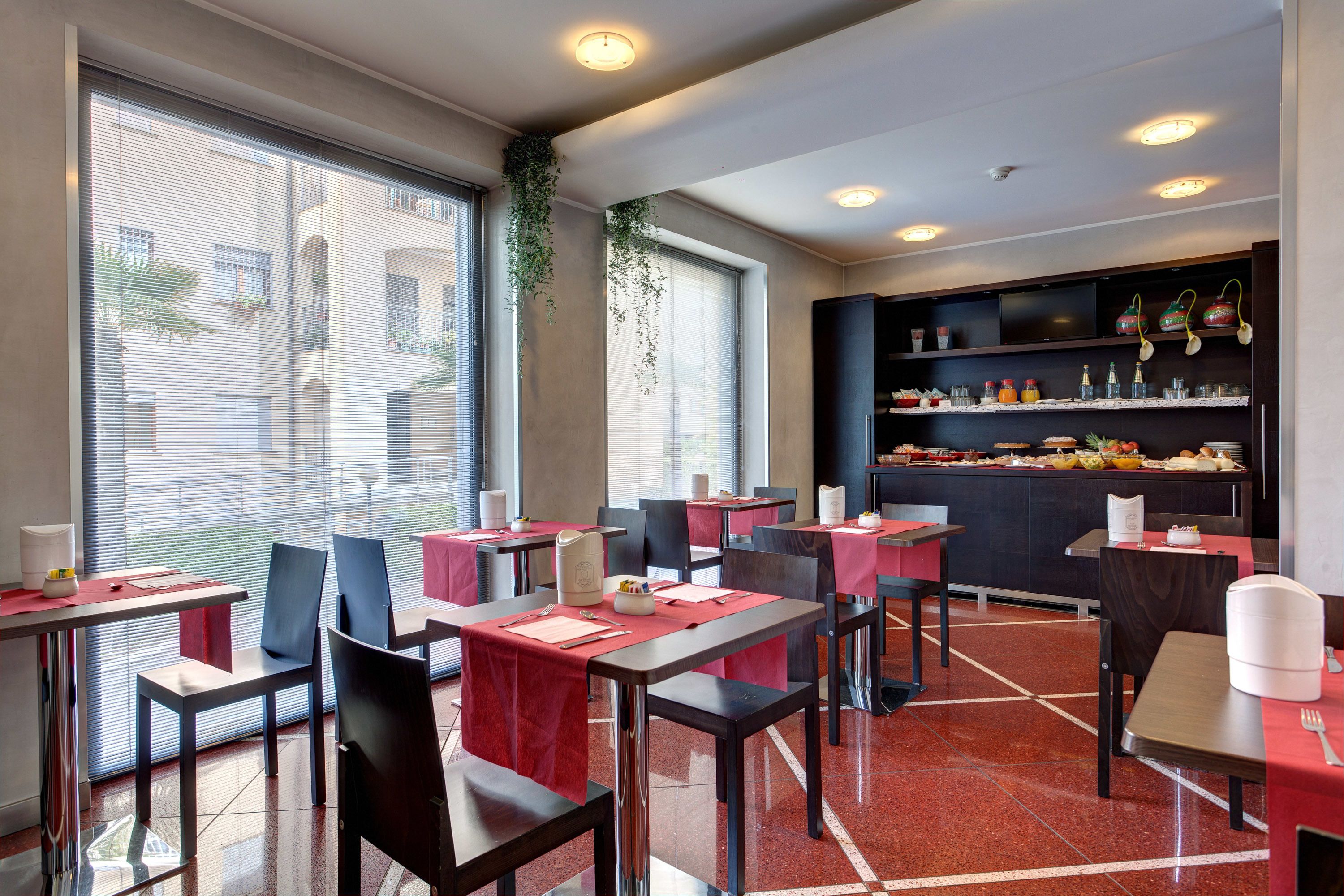 Un restaurante moderno con mesas y sillas rojas y negras, y una zona de bar central con estantes llenos de condimentos y botellas.