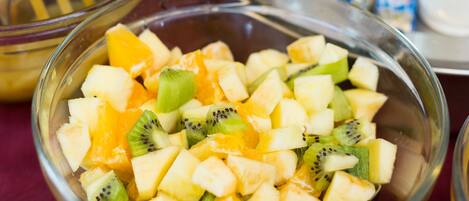 A breakfast buffet with various fruits, pastries, and yogurt cups.