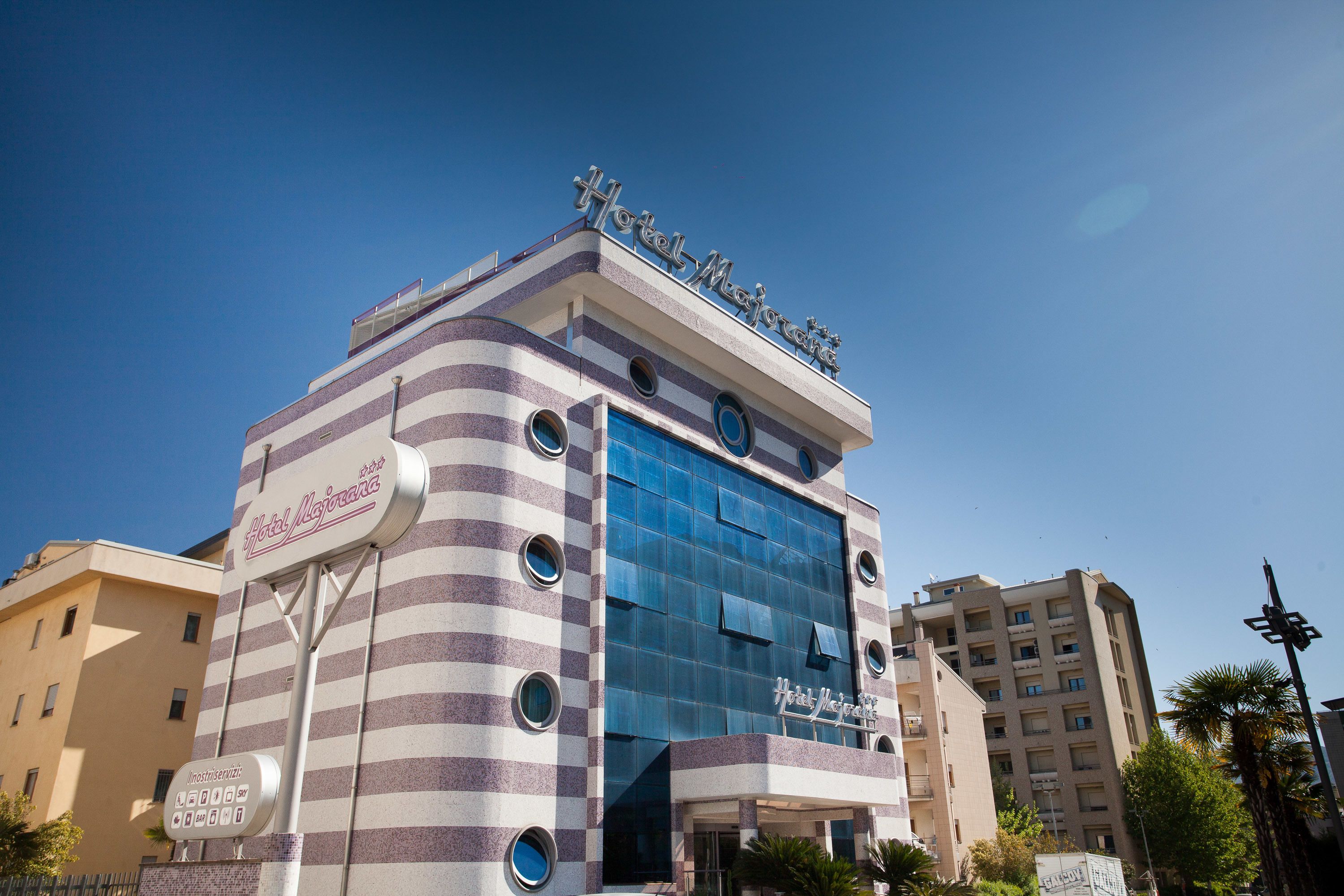 A hotel with a striped facade, a prominent sign, and a modern glass entrance.
