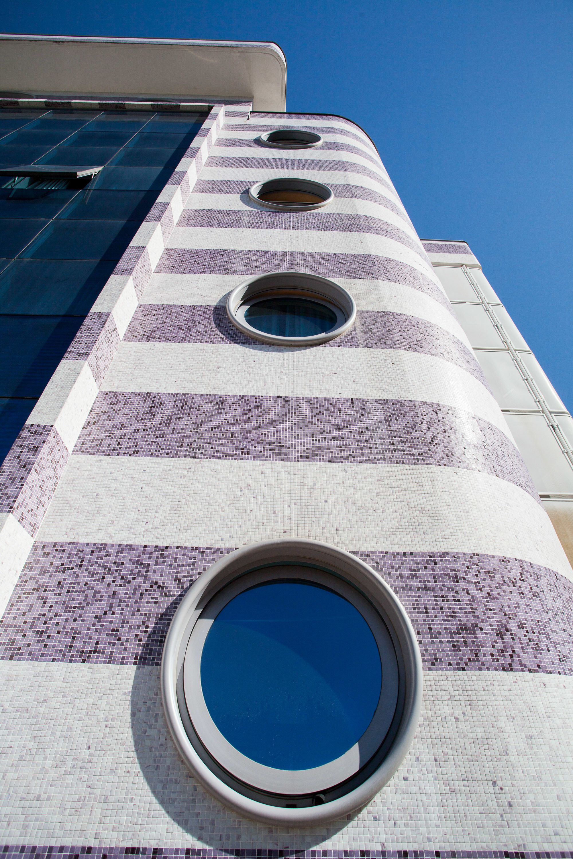 Un edificio con fachada a rayas y ventanas circulares.