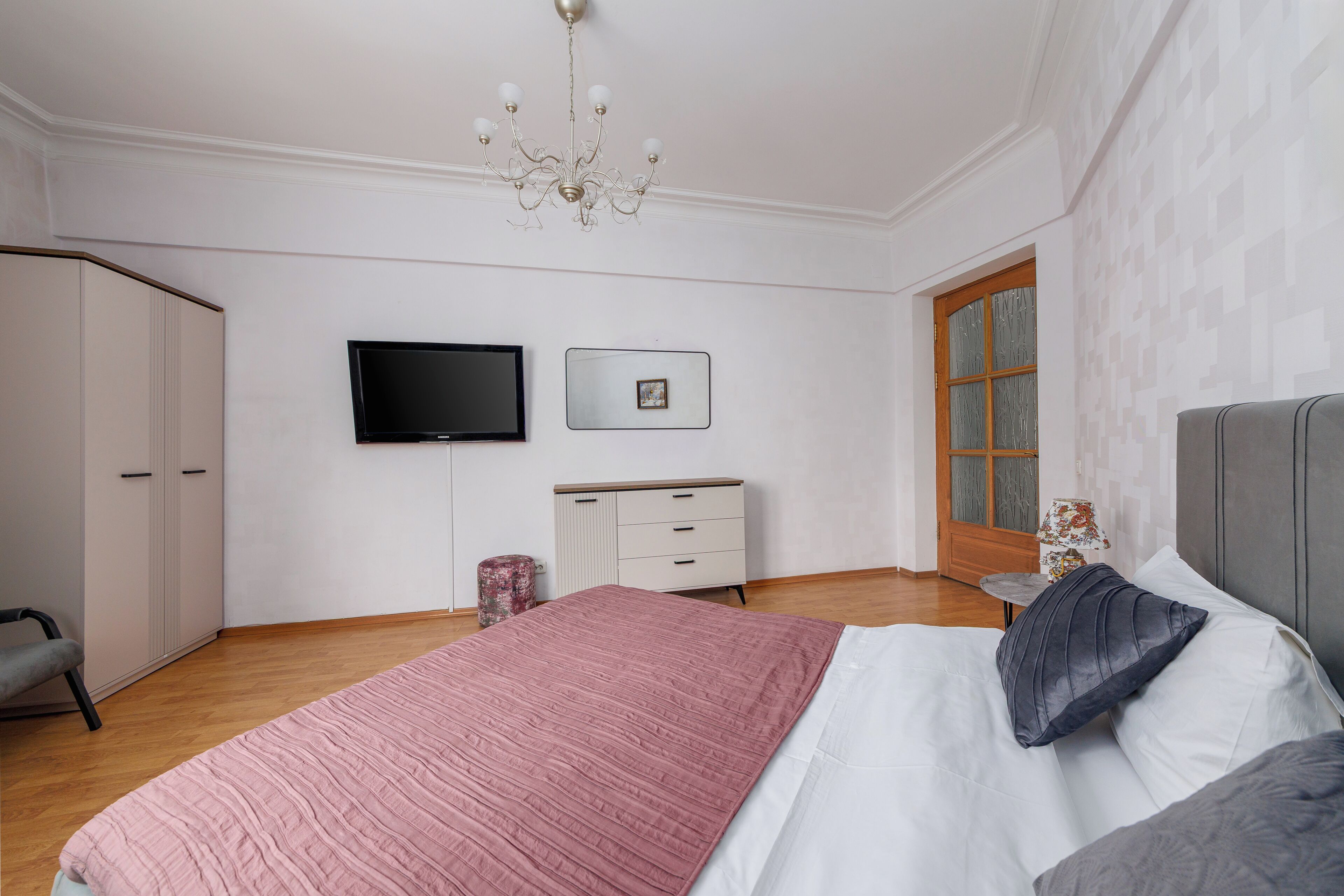A bedroom with a bed, a desk, a television, and a wardrobe.