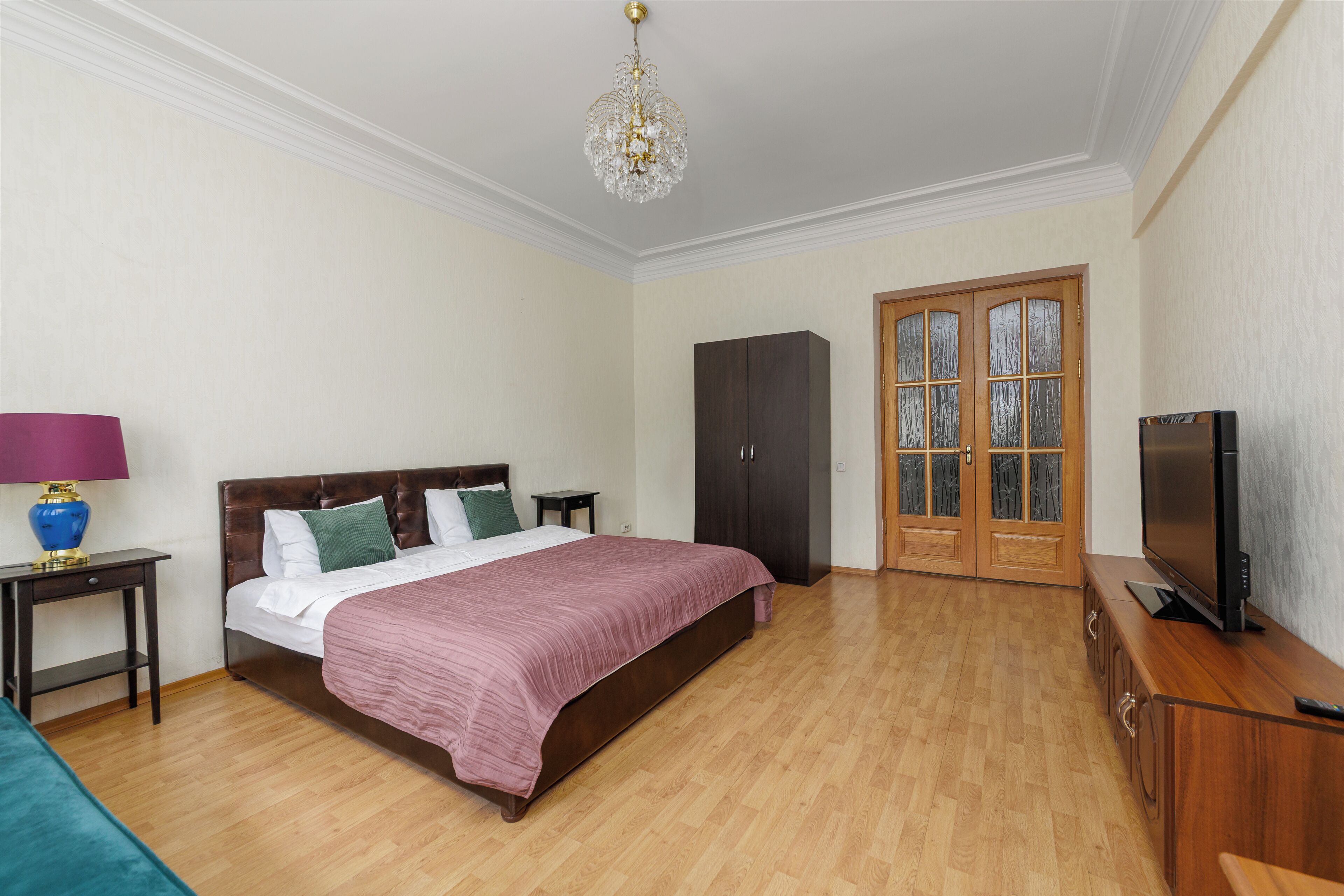 Un dormitorio con cama, armario, televisor y candelabro.