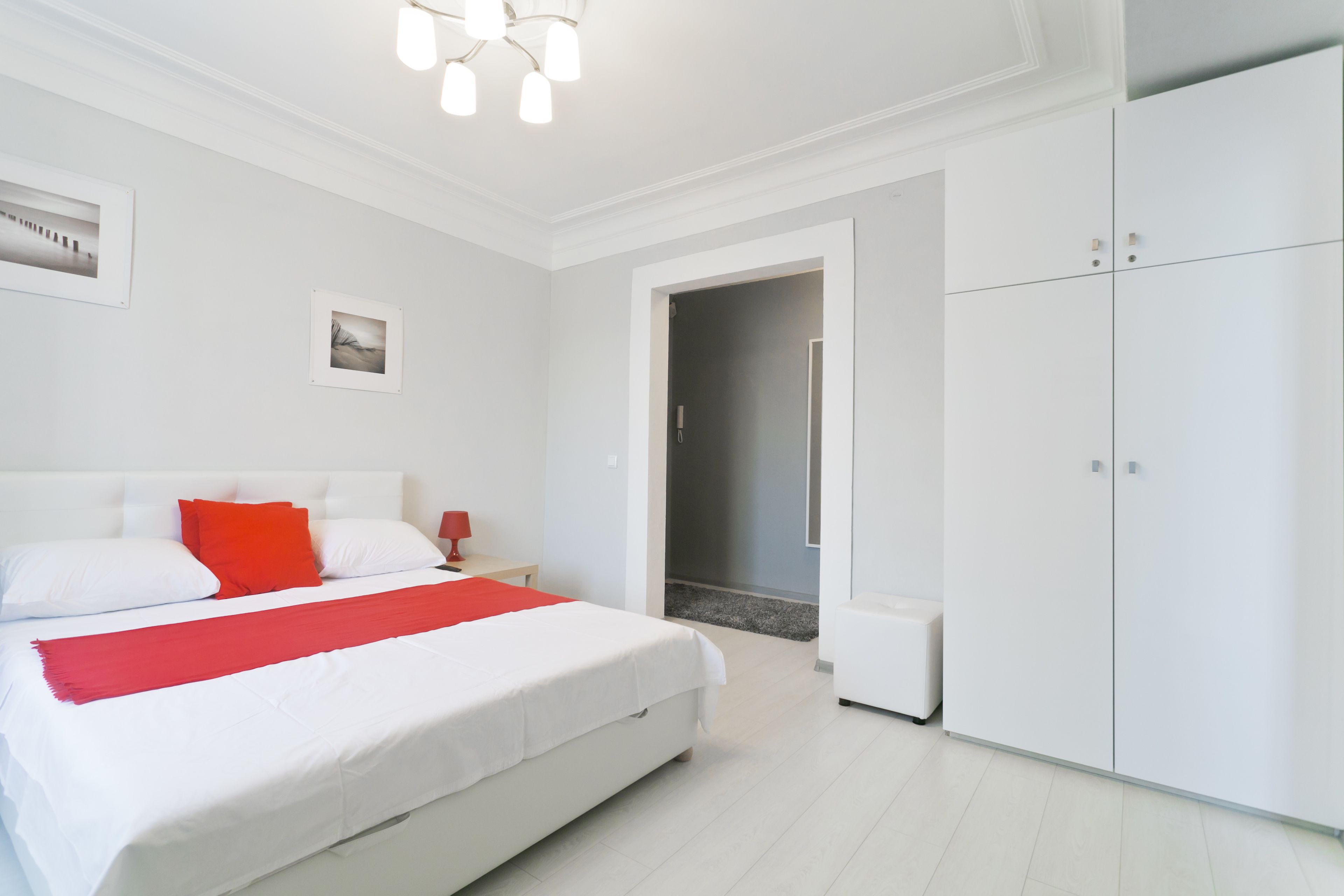 A modern bedroom with a large bed, white walls, and a wardrobe.