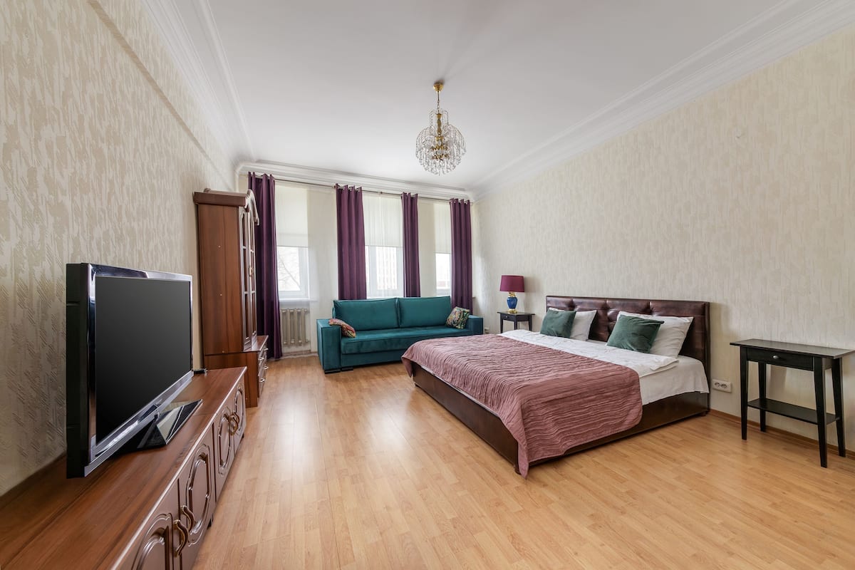 Une chambre à coucher avec un lit, une télévision, un canapé, une table et un lustre.