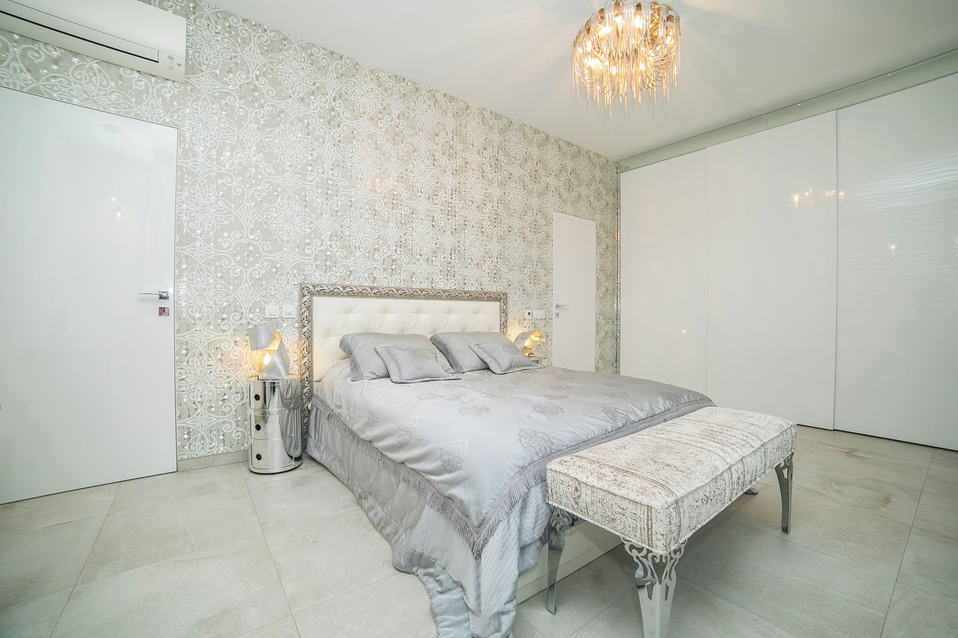 Une chambre à coucher avec un grand lit, une table de chevet avec une lampe et un lustre.