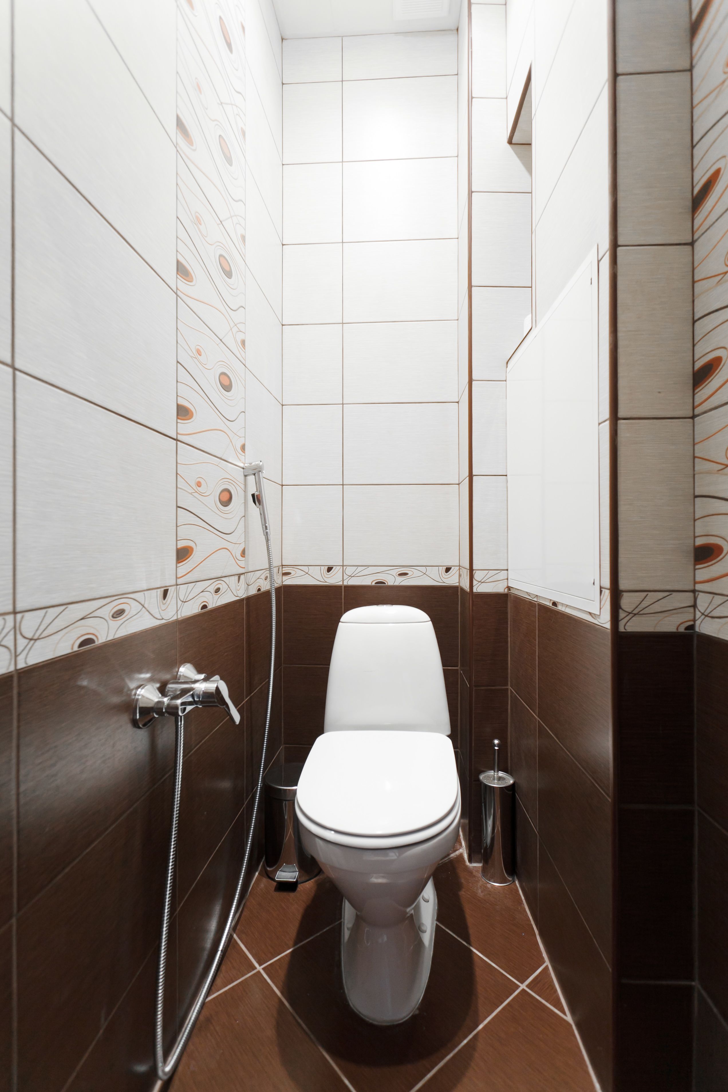 Un baño pequeño y moderno con inodoro blanco, ducha y dispensador de papel higiénico.