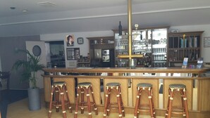 A bar area with a counter, stools, and a large plant. - Hotel & Restaurant Kuhfelder Hof (Kuhfelde)