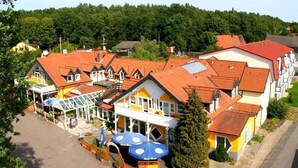 A hotel with multiple buildings, red-tiled roofs, and a central structure with a glass roof. - Hotel & Restaurant Kuhfelder Hof (Kuhfelde)