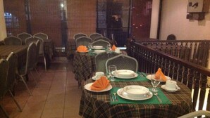 Un restaurante con mesas dispuestas para comer, sillas y una barandilla.