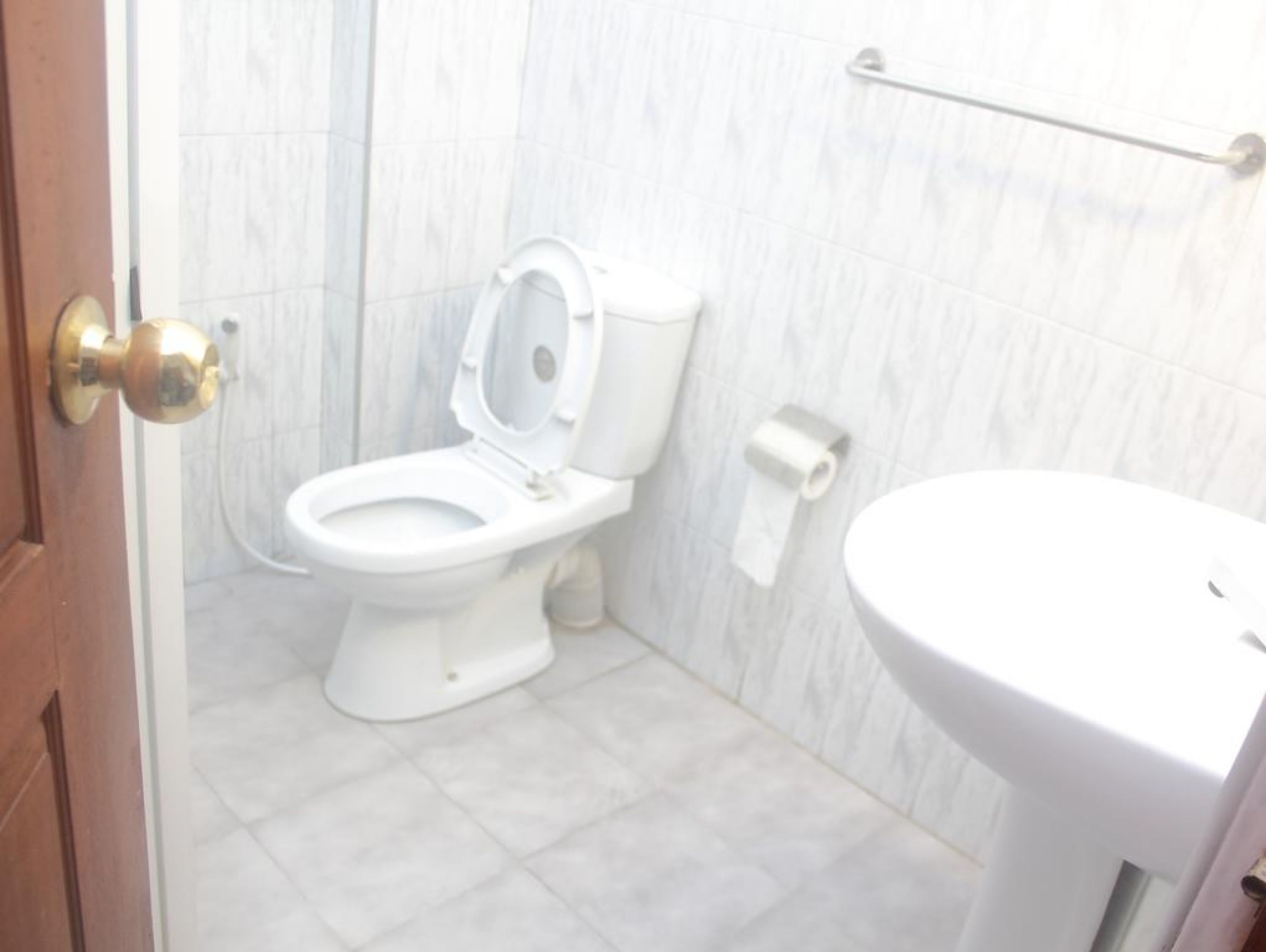 A bathroom with a white toilet, a white sink, and a marble wall.