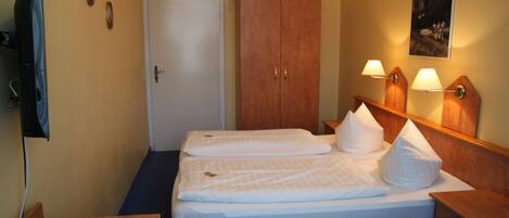 Habitación de hotel con cama, armario de madera, escritorio y lámparas de pared.