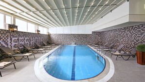 An indoor swimming pool with a tiled wall and lounge chairs. - B Business Hotel & Spa (Antalya)