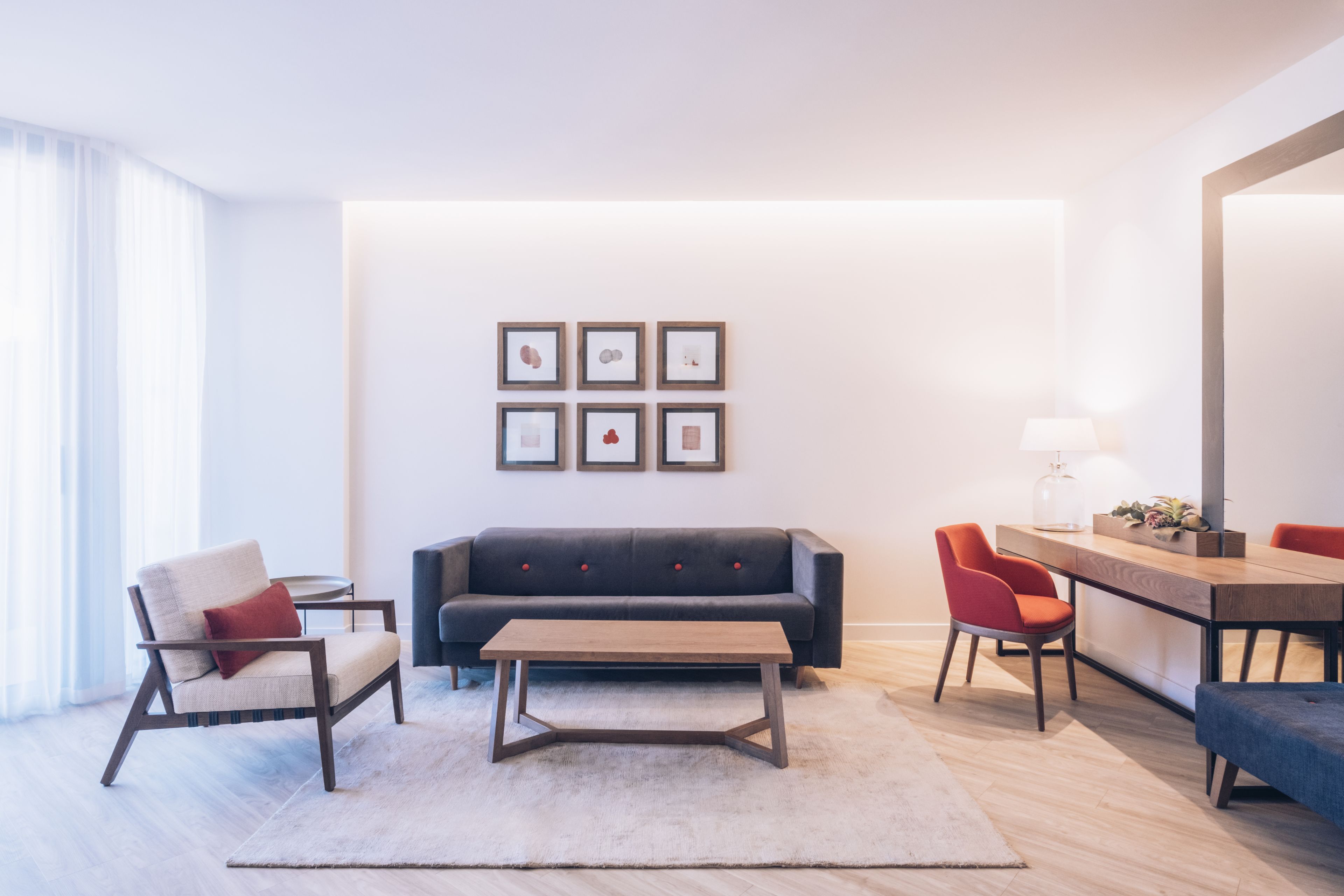 Una sala moderna con un sofá, sillones, una mesa de centro y un comedor con sillas y una mesa.