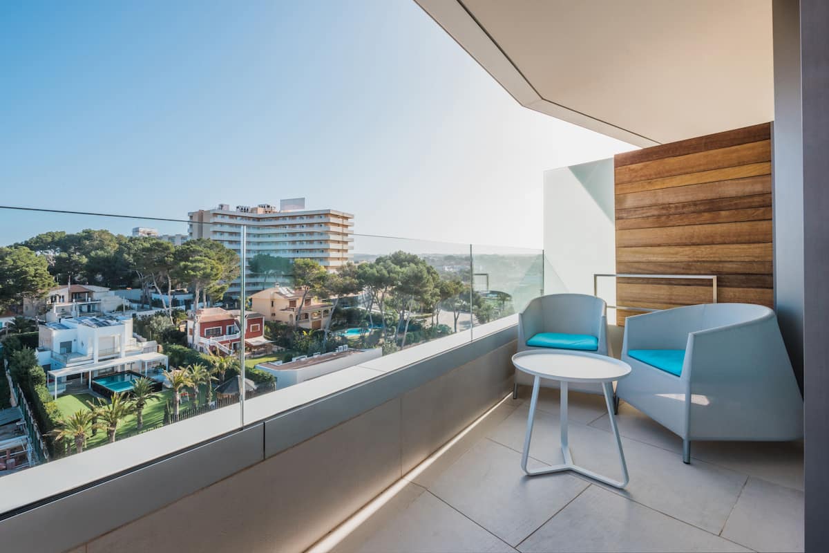 Ein moderner Balkon mit Blick auf eine Wohngegend, ein runder Tisch und ein blauer Sitzhocker.