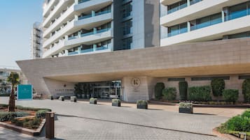 Hotel entrance with a prominent sign and landscaped gardens.