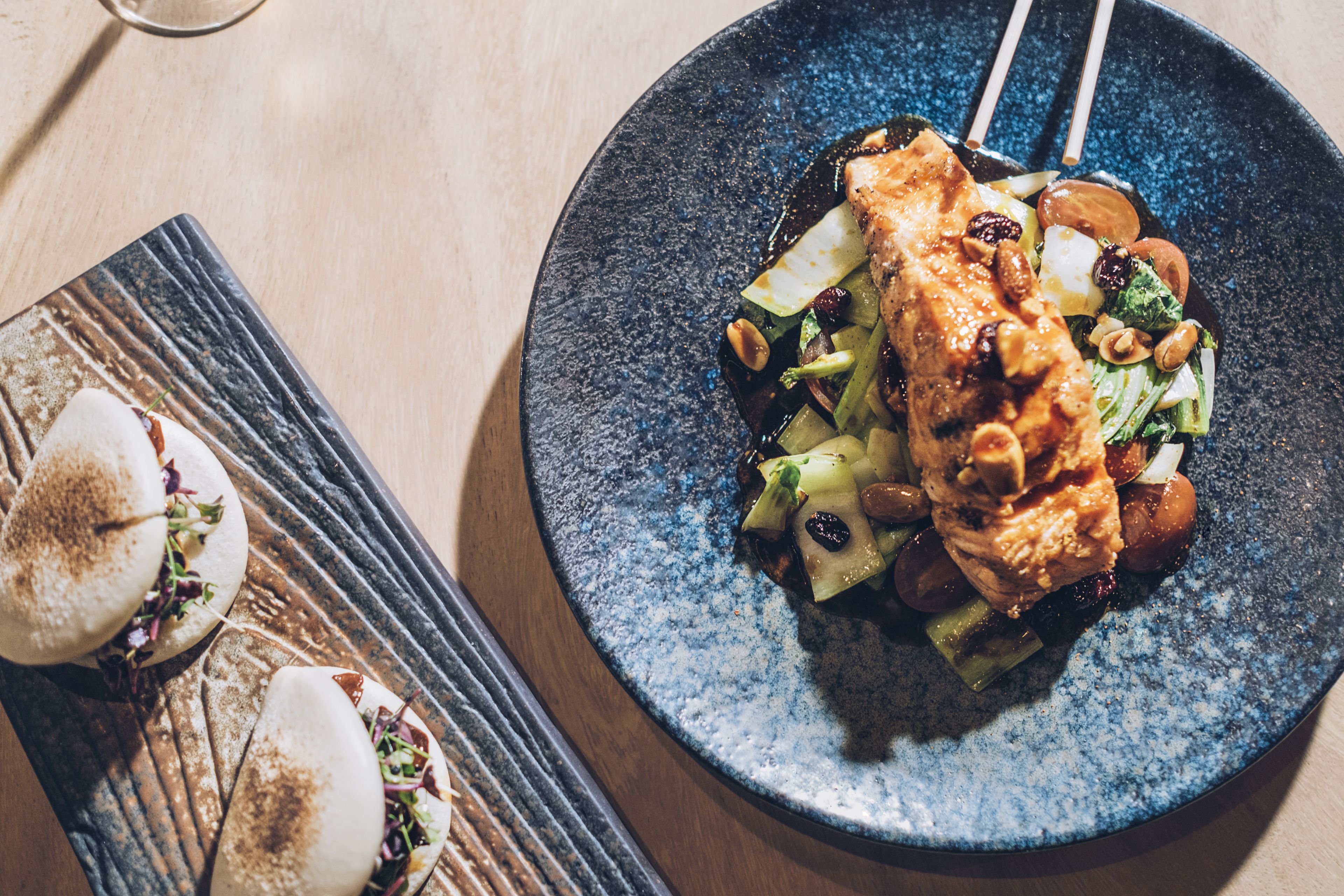 A plate with a piece of grilled chicken, vegetables, and nuts.